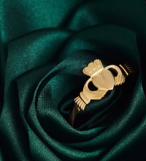 Gold claddagh ring on a dark green fabric background